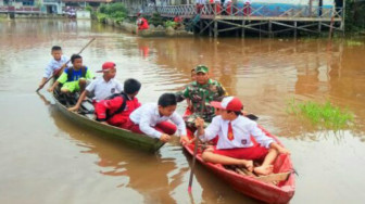 Akibat Banjir, Babinsa Bantu Anak–anak Kesekolah Gunakan Perahu