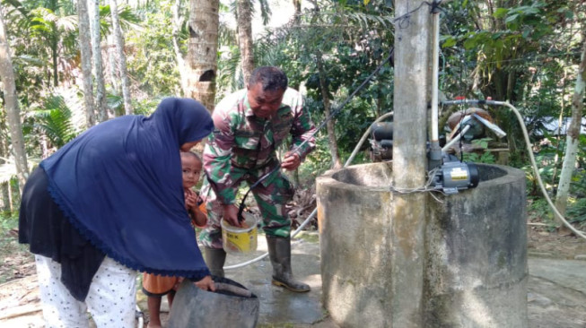 Babinsa Serda Bambang Bantu Orangtua Asuh Timba Air di Sumur